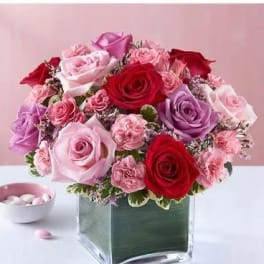 Pink and red rose arrangement in a square glass vase