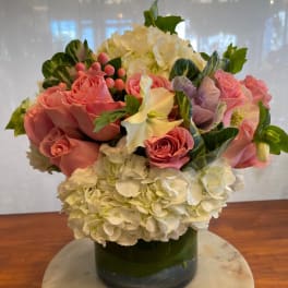 Pink roses and white hydrangeas arranged in a glass vase