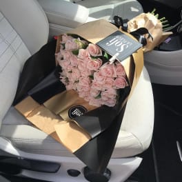 Bouquet of pale pink roses wrapped in black and tan paper