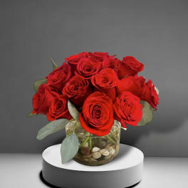 Red roses arranged in a glass vase with stones