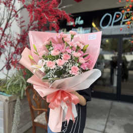 Pink bouquet with lilies, carnations, and baby's breath wrapped in pastel paper