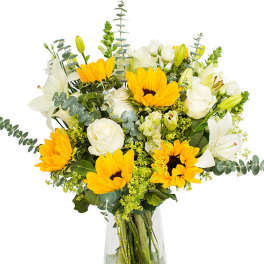 Bouquet of yellow sunflowers and white lilies in a clear glass vase