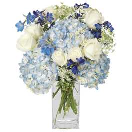 Blue hydrangeas and white roses in a clear glass vase