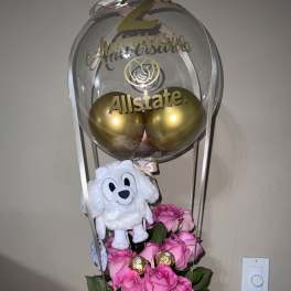 Pink roses with a plush dog and gold balloons in a clear balloon topper