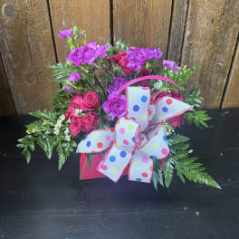 Pink roses and purple carnations in a gift box with a polka-dot bow