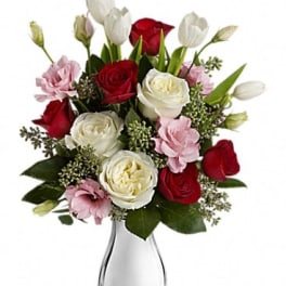 Bouquet of red and white roses with pink blooms in a clear glass vase