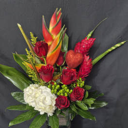 Red roses and white hydrangea in a glass vase with tropical blooms and a glitter heart