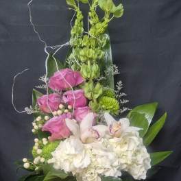 Tall floral arrangement with pink and white blooms in a glass vase