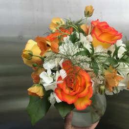 Bouquet of orange and yellow roses with white flowers in a glass vase