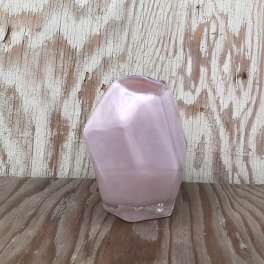 Small faceted pink glass vase on a rustic wooden surface
