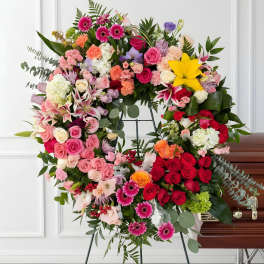 Large mixed floral wreath on an easel beside a casket