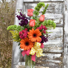 Bright mixed bouquet in a glass vase with orange daisies and pink roses