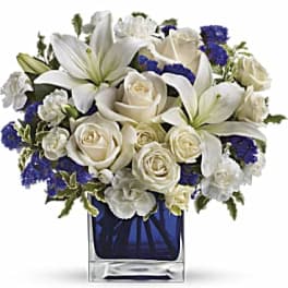 White lilies and roses arranged in a blue glass vase