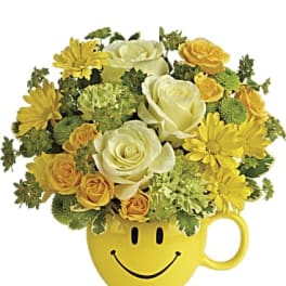 Yellow smiley-face mug filled with yellow and white flowers