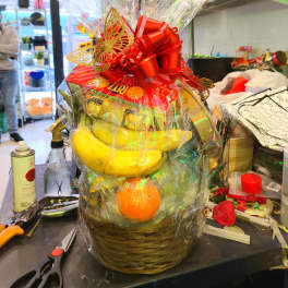 Gift basket with bananas, oranges, and chocolates wrapped in clear cellophane