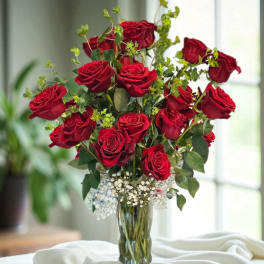 Red roses arranged in a clear glass vase with baby's breath