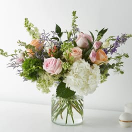 Mixed bouquet of pink and peach roses with white hydrangea in a glass vase