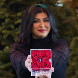 Woman holding a clear box of four red roses