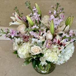 Bouquet of white lilies, roses, and pale pink flowers in a glass vase