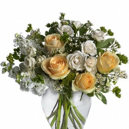 Cream and white roses arranged in a clear glass vase