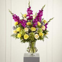 Yellow roses and purple flowers in a clear glass vase