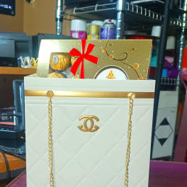 White gift bag with gold chain handles and a gold gift box inside