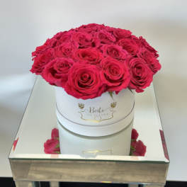 Round box of hot pink roses on a mirrored table