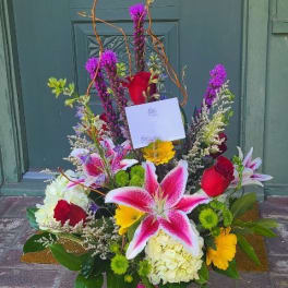 Colorful mixed flower arrangement in a glass vase with lilies and roses