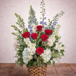 Red roses and blue-white flowers arranged in a woven basket