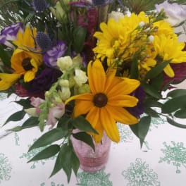 Mixed bouquet with yellow daisies, purple blooms, and white flowers in a pink vase