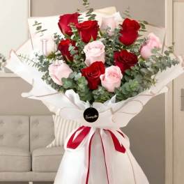 Bouquet of red and pale pink roses wrapped in white paper