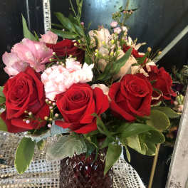 Bouquet of red roses, pink alstroemeria, and white carnations in a red vase