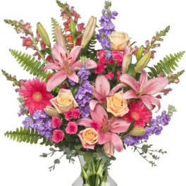 Mixed bouquet of pink lilies, roses, and purple flowers in a glass vase