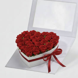 Heart-shaped box filled with red roses and tied with a red ribbon