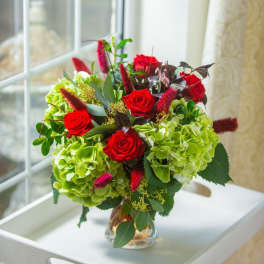 Red roses and green hydrangeas in a clear glass vase