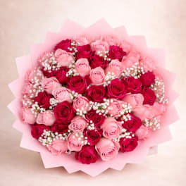 Round bouquet of pink and red roses with white filler flowers