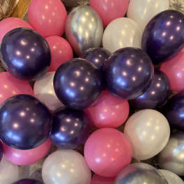 Cluster of pink, purple, white, and silver balloons on the floor