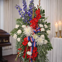 Standing floral spray with red, white, and blue flowers on an easel