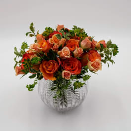 Orange and peach roses arranged in a clear glass vase