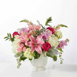 Pink lilies and roses arranged in a white vase