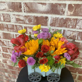 Mixed bouquet in a blue wooden cart with red, yellow, and purple flowers