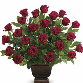 Large arrangement of red roses in a dark pedestal vase