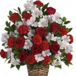 Red roses, red carnations, and white alstroemeria arranged in a woven basket