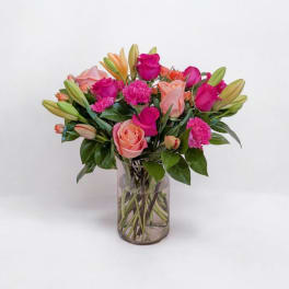 Pink and peach roses with lilies and carnations in a glass vase