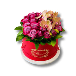 Pink roses and orchids arranged in a red hat box