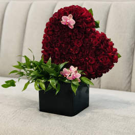 Heart-shaped red rose arrangement in a black box with pink orchids