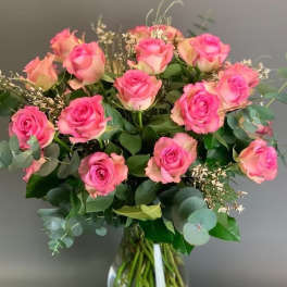 Pink roses arranged in a clear glass vase with eucalyptus
