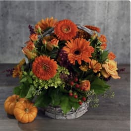 Orange floral basket with pumpkins on a gray table