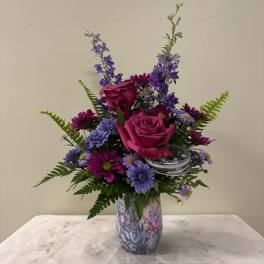 Pink roses and purple flowers arranged in a patterned vase