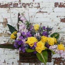 Yellow and purple roses arranged in a rustic basket